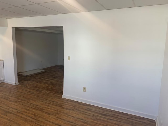 spare room featuring dark hardwood / wood-style floors and a drop ceiling