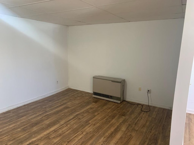 spare room featuring dark hardwood / wood-style flooring, a paneled ceiling, and heating unit