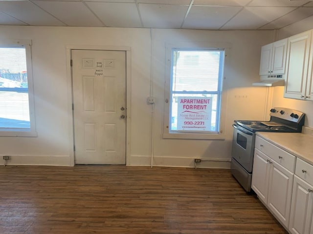 kitchen with stainless steel range with electric cooktop, dark hardwood / wood-style floors, a paneled ceiling, and white cabinetry