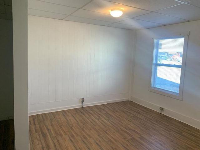 empty room with a drop ceiling and dark wood-type flooring