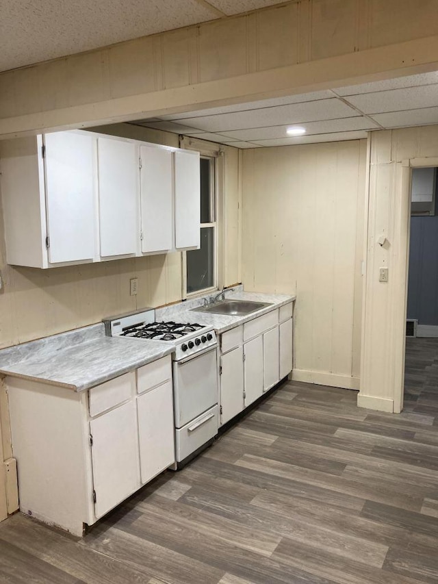 kitchen with white gas range, dark hardwood / wood-style floors, white cabinets, and sink