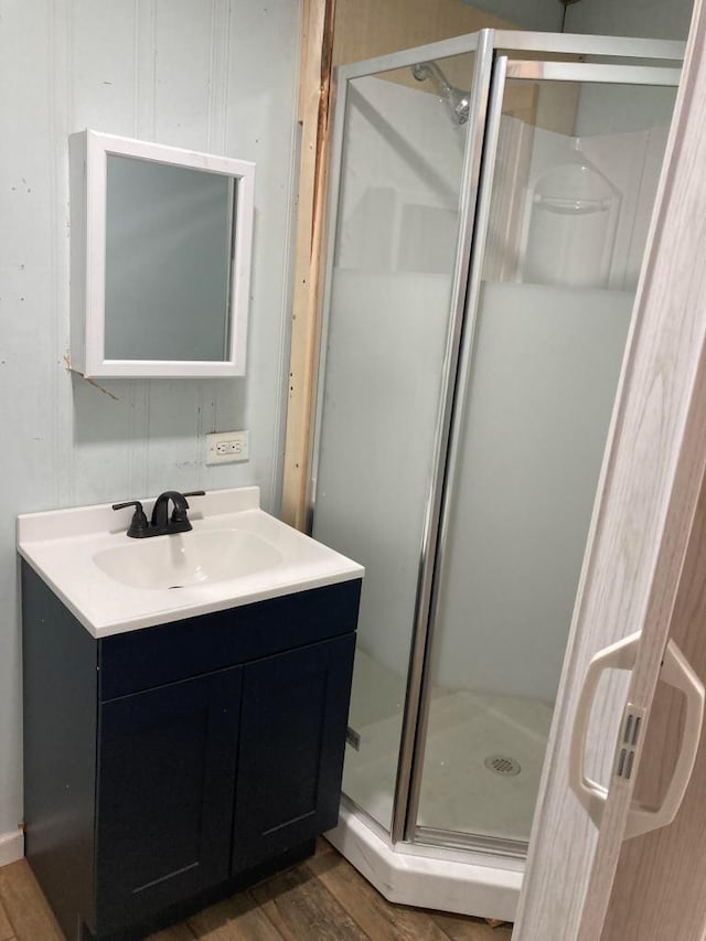 bathroom with hardwood / wood-style flooring, walk in shower, and vanity