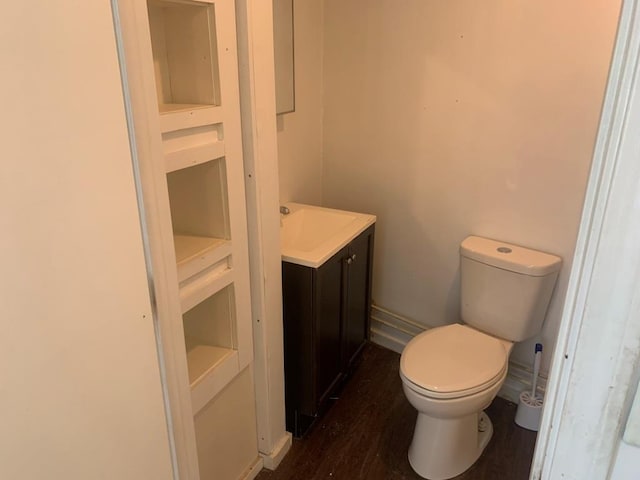 bathroom featuring toilet, hardwood / wood-style flooring, built in features, and vanity