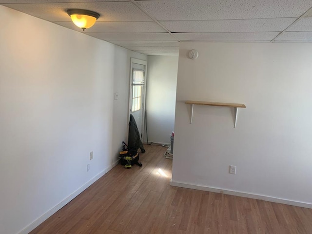 unfurnished room with a drop ceiling and hardwood / wood-style flooring