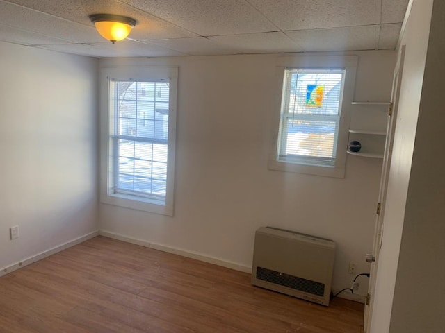 spare room featuring hardwood / wood-style flooring, a paneled ceiling, and heating unit