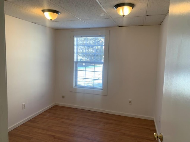 spare room featuring a paneled ceiling, plenty of natural light, and hardwood / wood-style flooring