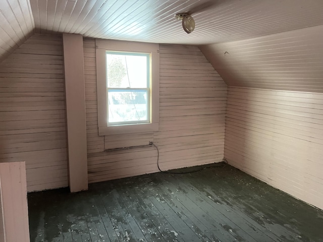 additional living space with lofted ceiling, dark hardwood / wood-style flooring, and wood walls