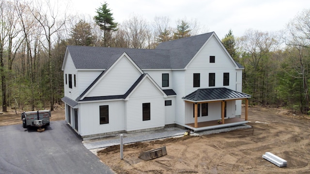 5 Red Oak Dr, Falmouth, ME 04105 - modern inspired farmhouse featuring covered porch, a shingled roof, a view of trees, asphalt driveway, and an attached garage