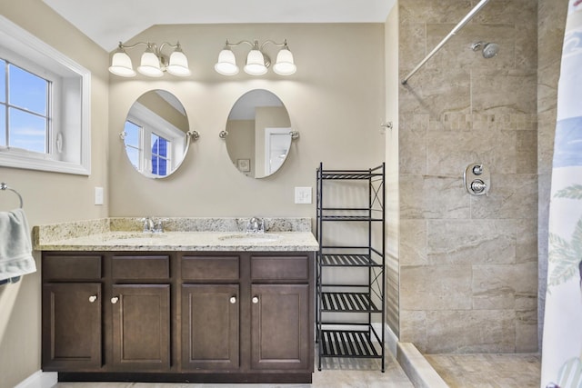 bathroom with a tile shower and vanity