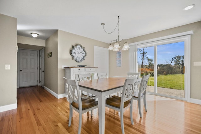 dining space featuring light wood-type flooring and an inviting chandelier