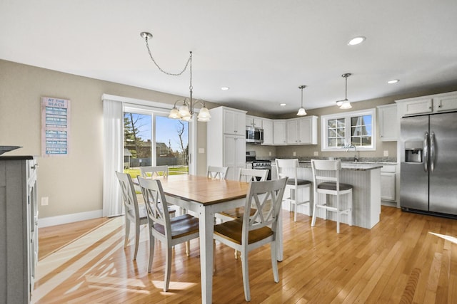 dining room with sink, light hardwood / wood-style floors, and a notable chandelier