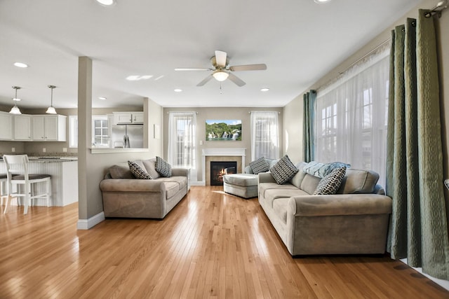 living room with light wood-type flooring and ceiling fan