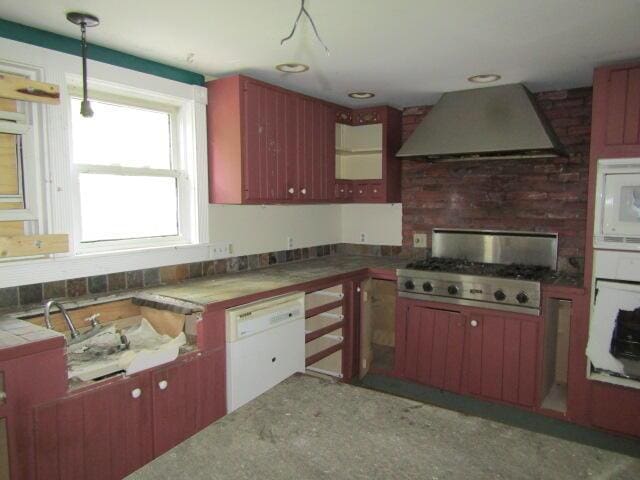 kitchen featuring wall chimney exhaust hood, white appliances, and decorative light fixtures