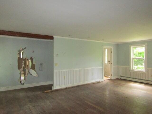 empty room featuring dark hardwood / wood-style floors, crown molding, and baseboard heating