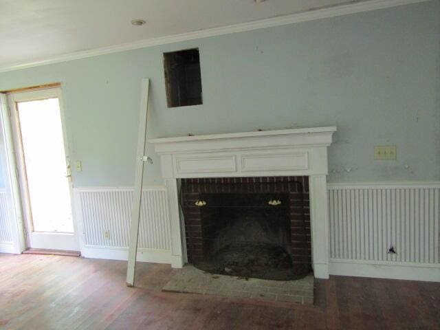 unfurnished living room with radiator heating unit, wood-type flooring, ornamental molding, and a brick fireplace