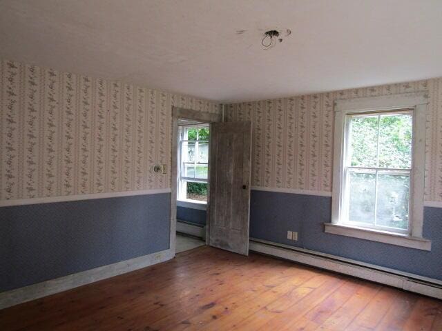 empty room featuring hardwood / wood-style flooring and a baseboard radiator