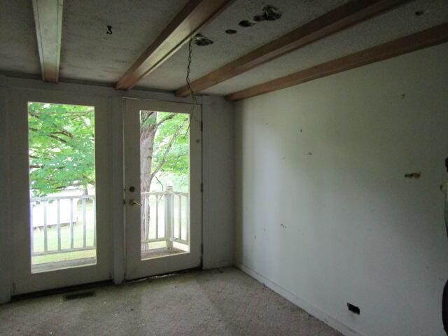 empty room featuring beam ceiling and plenty of natural light