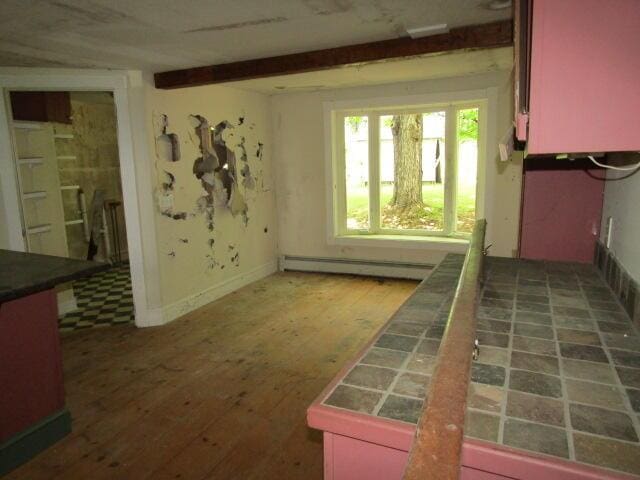 interior space featuring beam ceiling, tile countertops, and baseboard heating