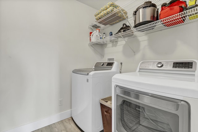 laundry room with separate washer and dryer and light hardwood / wood-style flooring