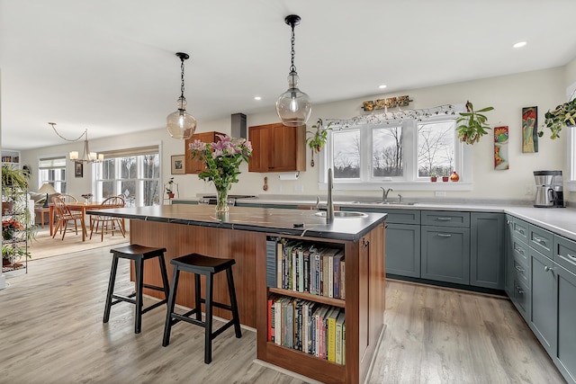 kitchen featuring a chandelier, a center island, light wood-type flooring, a kitchen breakfast bar, and sink