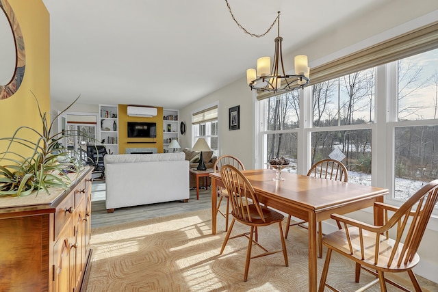 dining area featuring a wall unit AC, a healthy amount of sunlight, and a notable chandelier