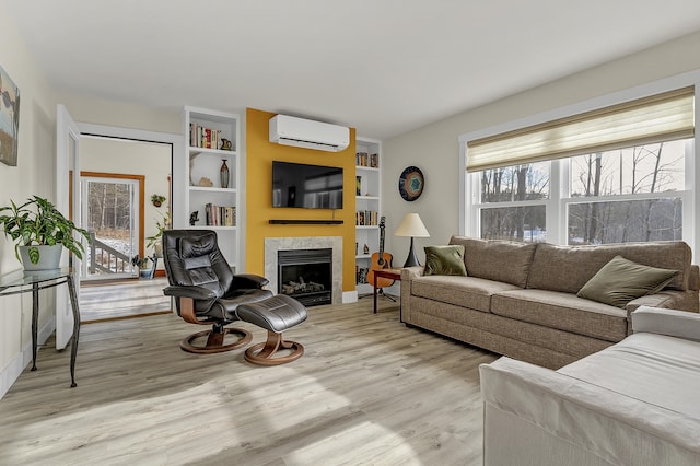 living room featuring a tile fireplace, light wood-type flooring, a wall unit AC, and built in shelves