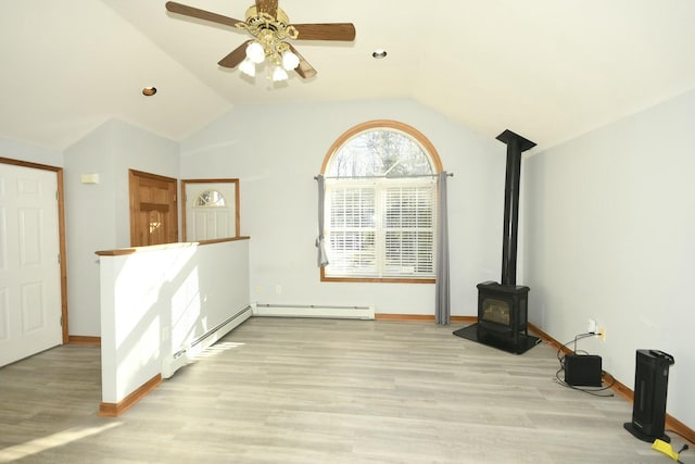 unfurnished living room featuring a baseboard radiator, a wood stove, ceiling fan, and lofted ceiling