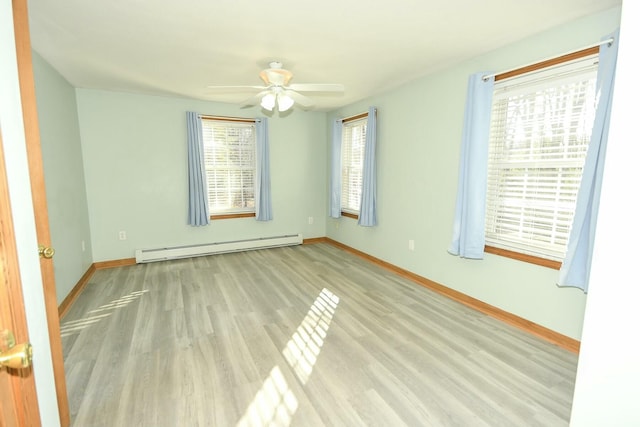 empty room featuring ceiling fan, baseboard heating, and light hardwood / wood-style flooring