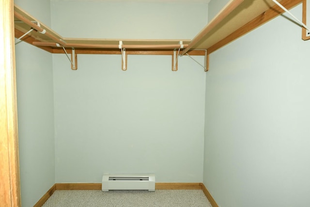 spacious closet featuring light colored carpet and a baseboard radiator