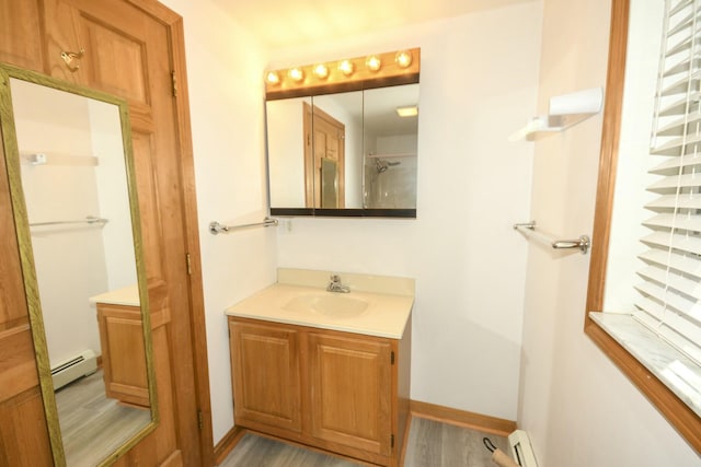 bathroom with hardwood / wood-style floors, vanity, and a baseboard heating unit