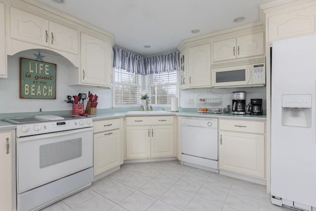 kitchen with sink, white appliances, and cream cabinets