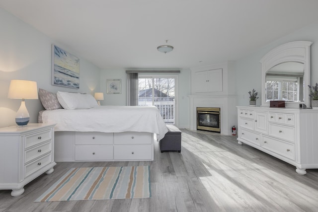 bedroom featuring multiple windows, access to outside, and light wood-type flooring