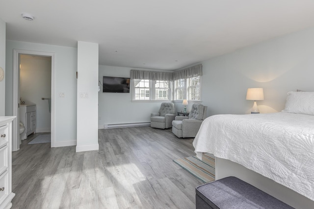 bedroom featuring light wood-type flooring and a baseboard heating unit