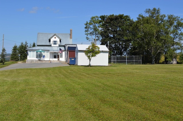 exterior space with metal roof, a lawn, a chimney, and fence