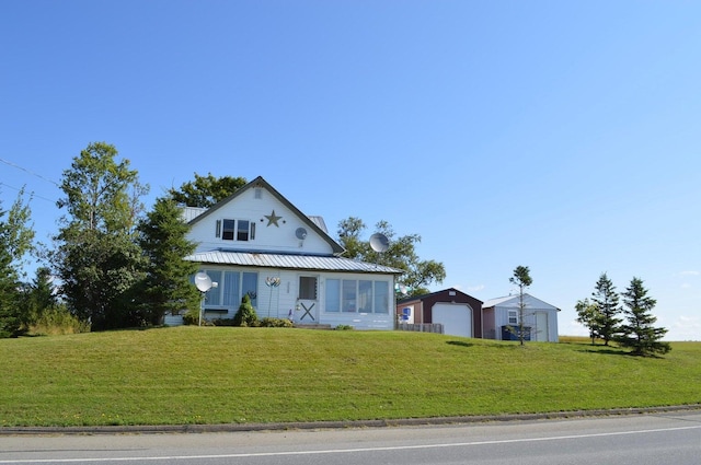 view of front of home with a garage, metal roof, and a front lawn