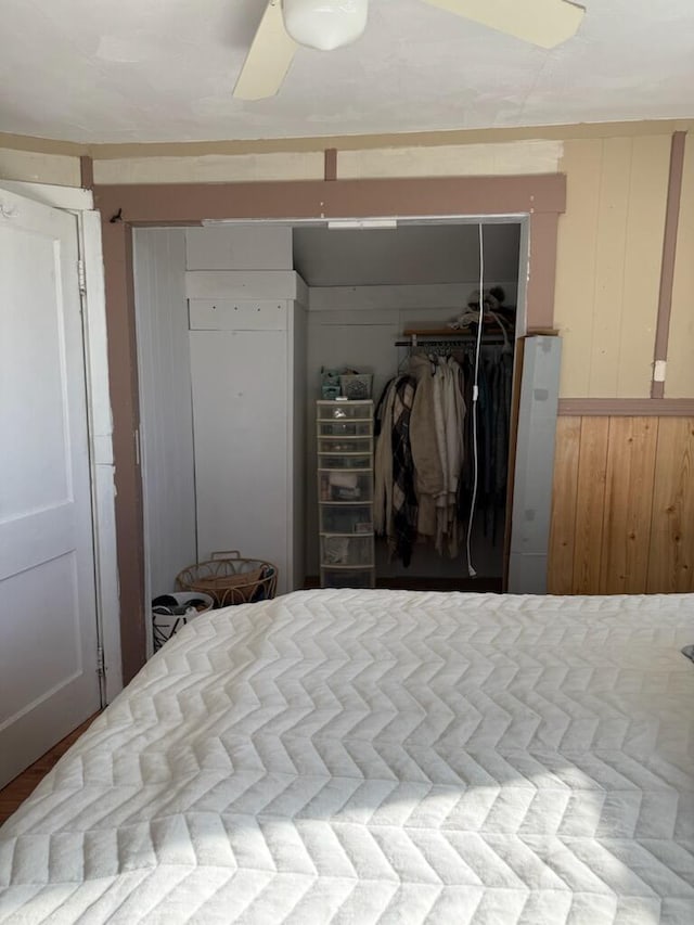 bedroom with a ceiling fan, a closet, and wooden walls