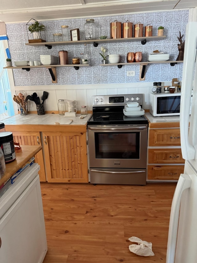 kitchen with white appliances, light countertops, light wood-style flooring, and open shelves