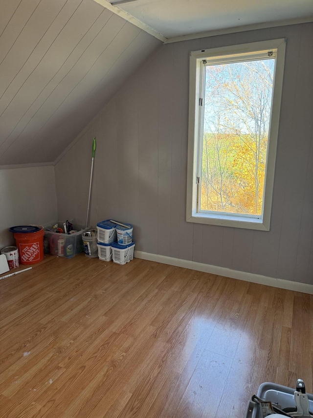 bonus room featuring light wood-type flooring, baseboards, and vaulted ceiling