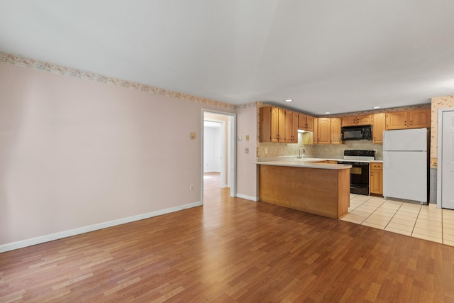 kitchen featuring white fridge, light hardwood / wood-style floors, range with electric cooktop, kitchen peninsula, and sink