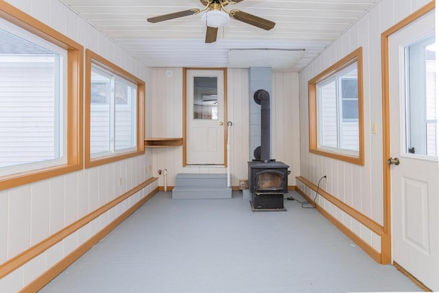 sunroom featuring ceiling fan and a wood stove