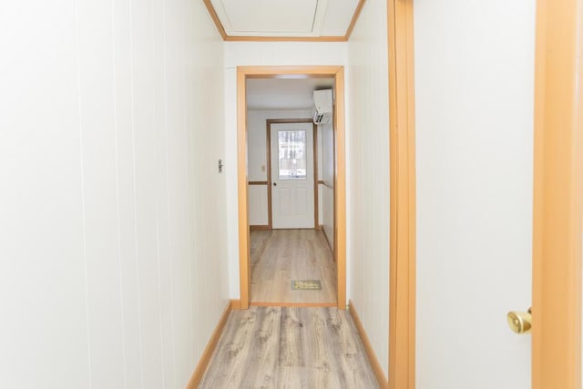 corridor featuring light hardwood / wood-style flooring, a wall mounted air conditioner, and crown molding