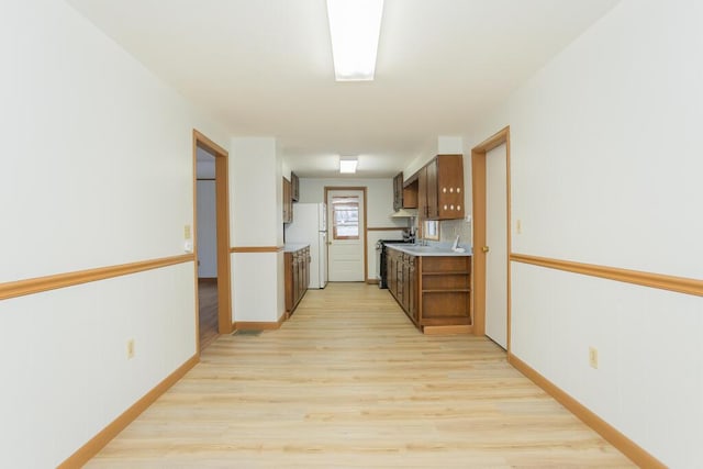 kitchen with light hardwood / wood-style floors, white refrigerator, and stainless steel gas stove