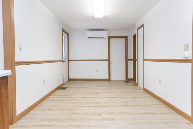 unfurnished room with light wood-type flooring and a wall mounted air conditioner