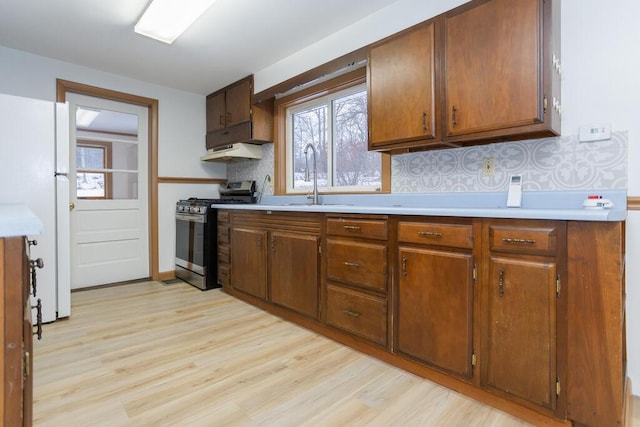 kitchen with gas range, white fridge, decorative backsplash, and sink