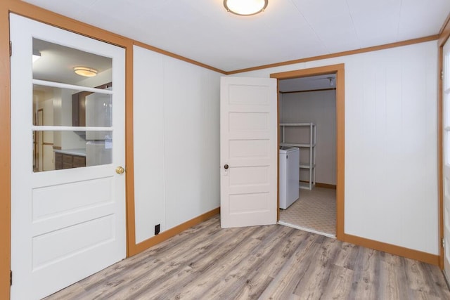 unfurnished bedroom featuring washer / dryer, light hardwood / wood-style floors, crown molding, and a closet