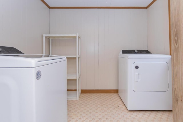 laundry room with wood walls, washing machine and clothes dryer, and crown molding