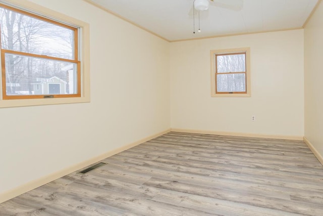 unfurnished room featuring light hardwood / wood-style floors, crown molding, and plenty of natural light