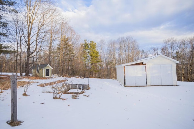 yard layered in snow with a garage and an outdoor structure