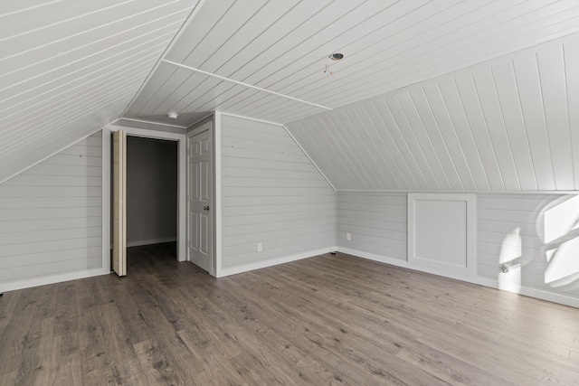 additional living space with lofted ceiling, wood-type flooring, and wooden walls