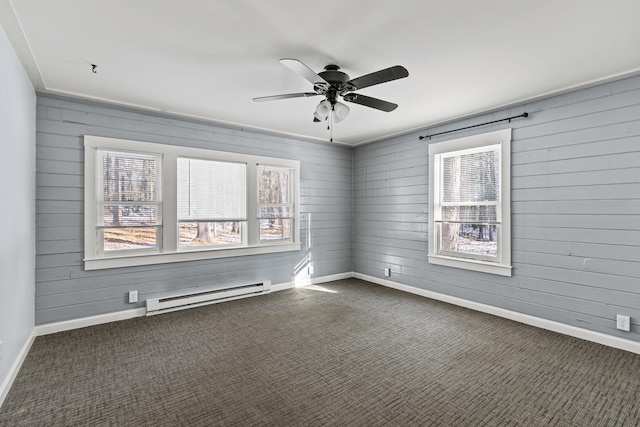 carpeted empty room with wood walls, ceiling fan, and a baseboard radiator